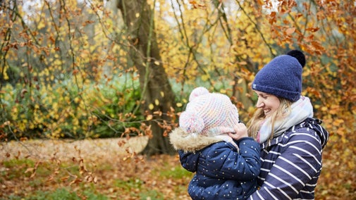 Woman carrying her son in an autumnal garden